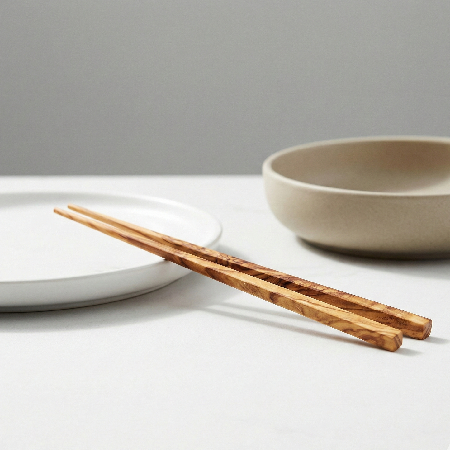 Wooden chopsticks on a white surface with a gray background