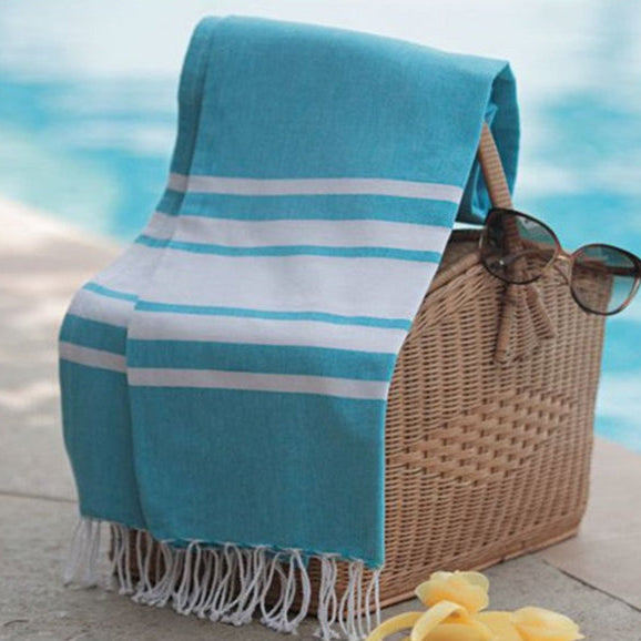 handmade Fouta towel turquoise blue folded -and drapped on a picnic, beach basket