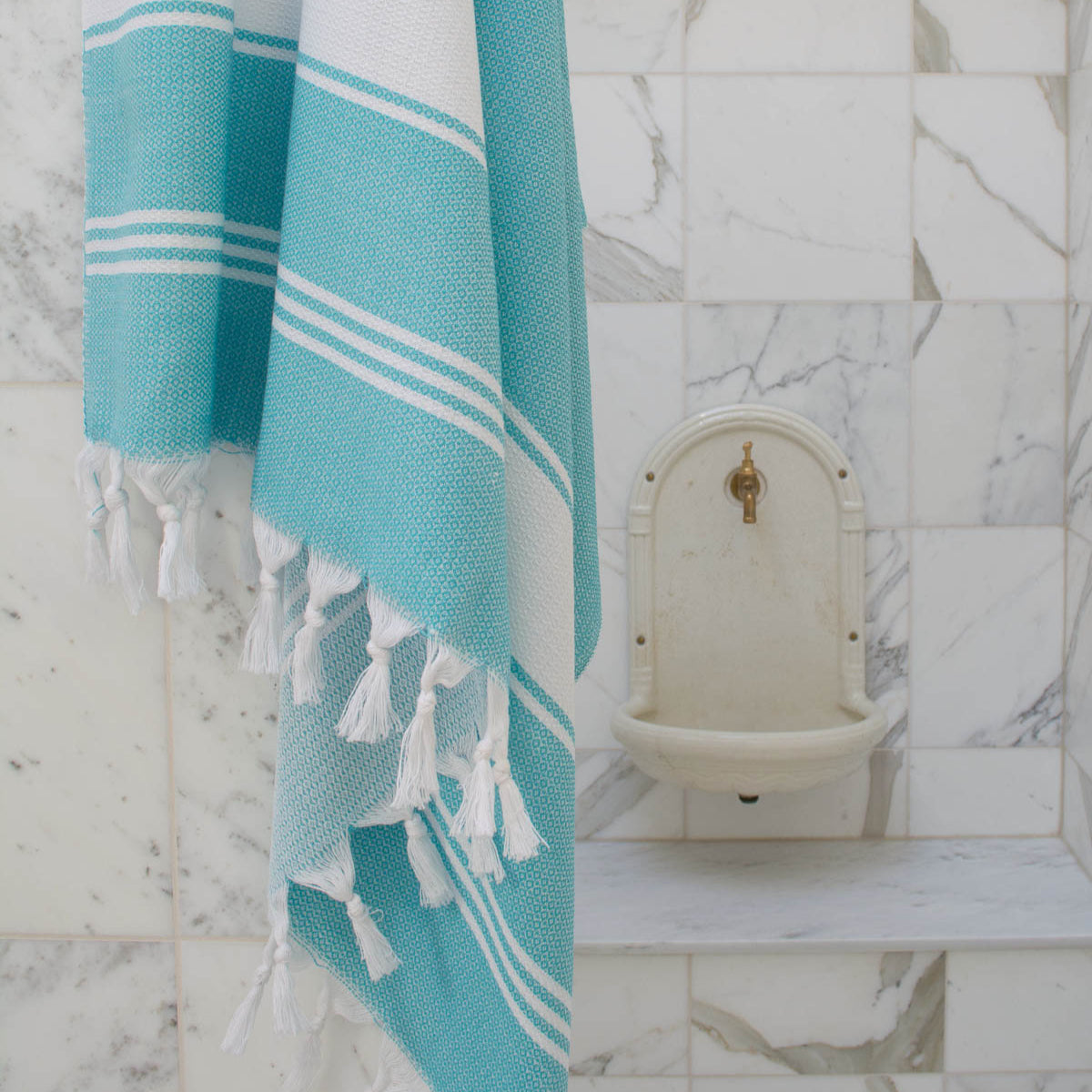 Turquoise blue hammam fouta towel, lightweight, quick-dry & beach towel.
Fouta towel turquoise blue draped on a wall