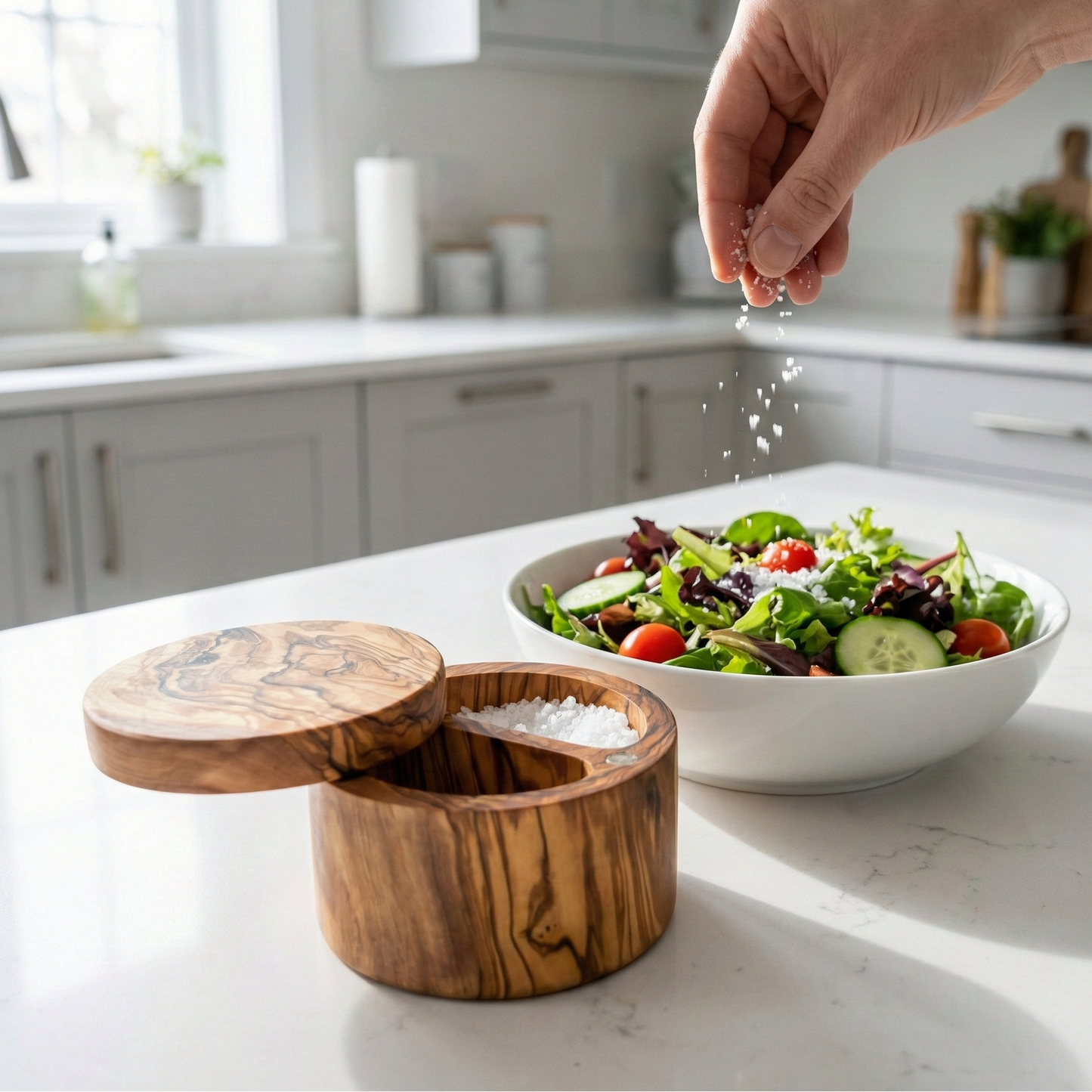 Person seasoning a salad with a wooden salt container in a kitchen.