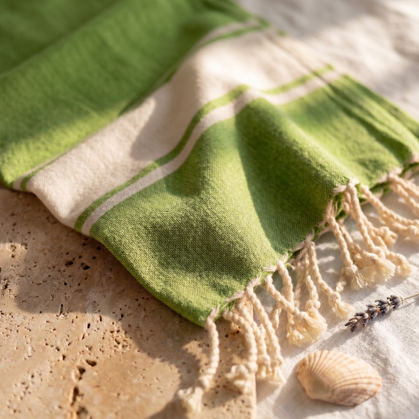 Close-up of citrus green fouta towel fabric revealing the fine cotton weave, soft texture, subtle pattern, and handcrafted fringed edges.