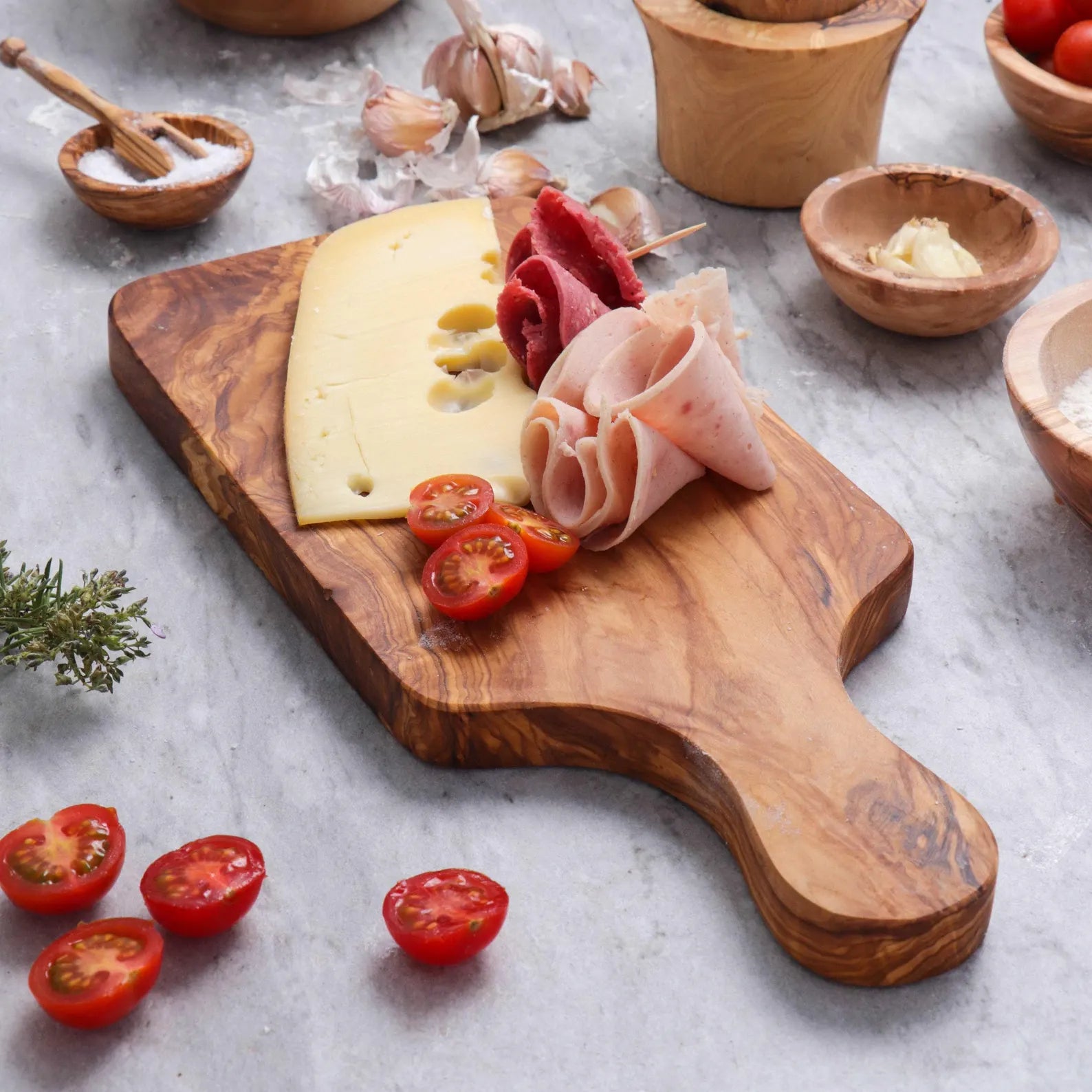 Handmade olive wood cutting board used as a serving board for cheese, bread, fruits, and charcuterie.