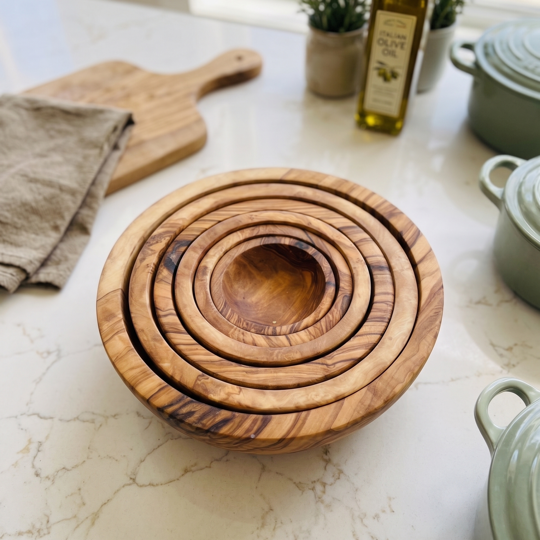 Set of six handcrafted olive wood nesting bowls stacked together, showcasing artisan craftsmanship, displayed on a white marble kitchen countertop.