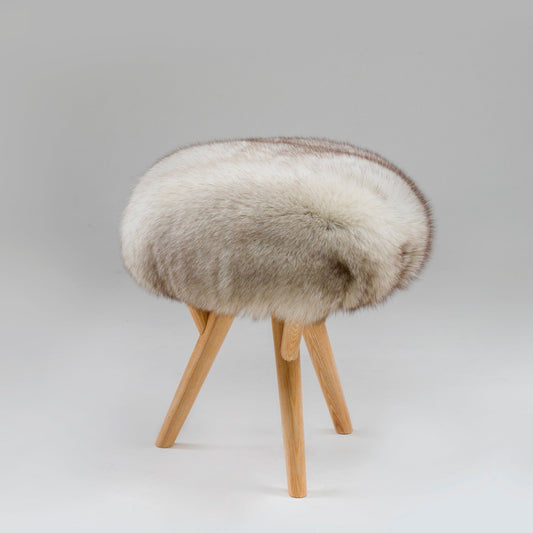 Vintage stool upholstered in genuine fox fur with handcrafted wooden legs against a grey background.