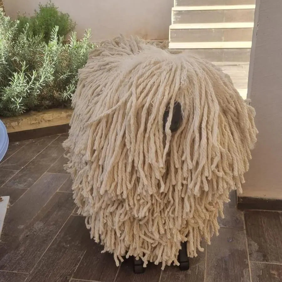 Fuzzy white dog toy resembling a sheep on a wooden floor.