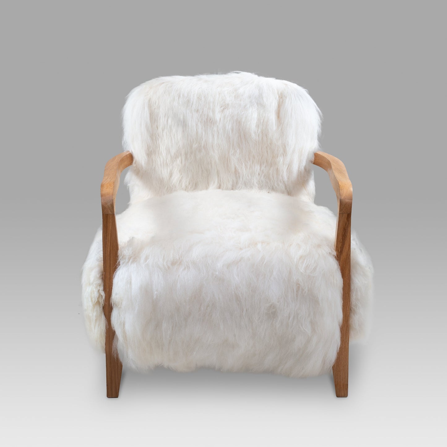 Luxury handmade Merino lambskin armchair with a sturdy natural wood frame, designed for elegant living spaces and modern interiors.