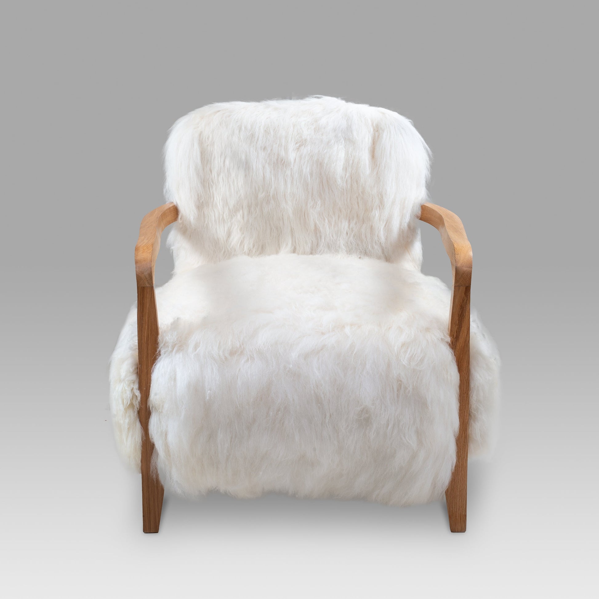 Luxury handmade Merino lambskin armchair with a sturdy natural wood frame, designed for elegant living spaces and modern interiors.