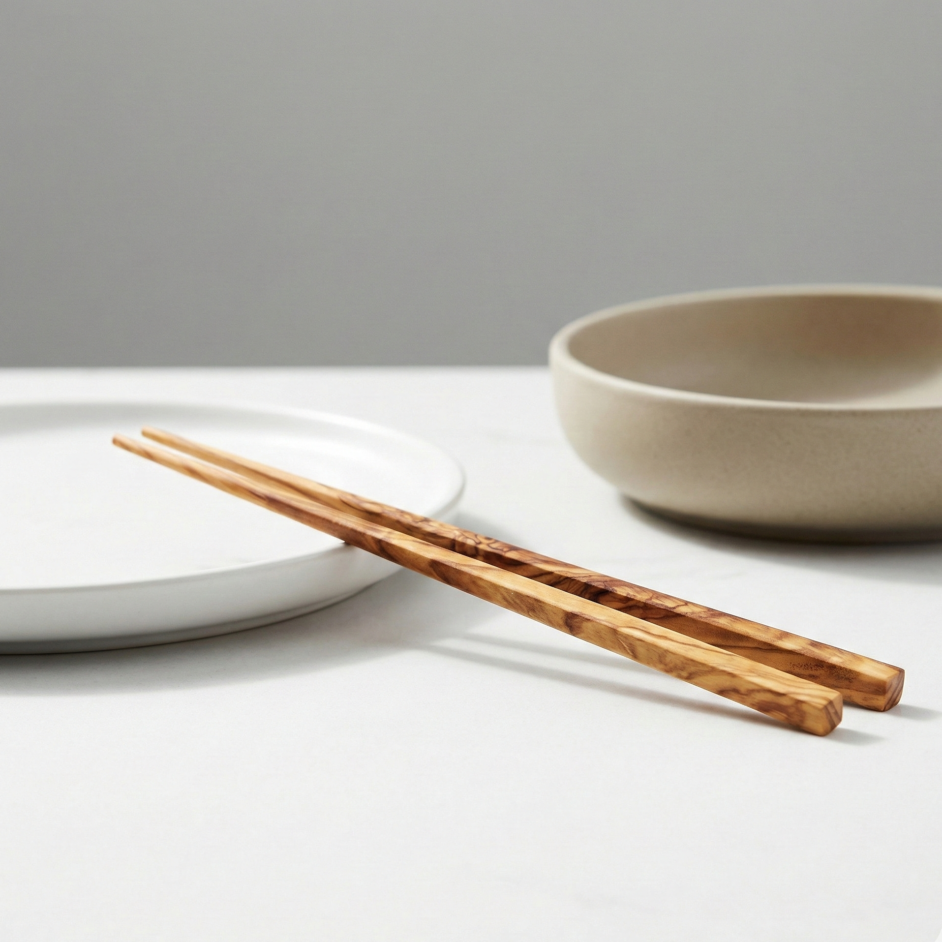 Wooden chopsticks on a white surface with a gray background